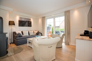 A modern living room with a sofa, chairs, a coffee table, and a TV. - Modern vacation home with its own sauna, whirlpool bath and terrace (Tinnum)