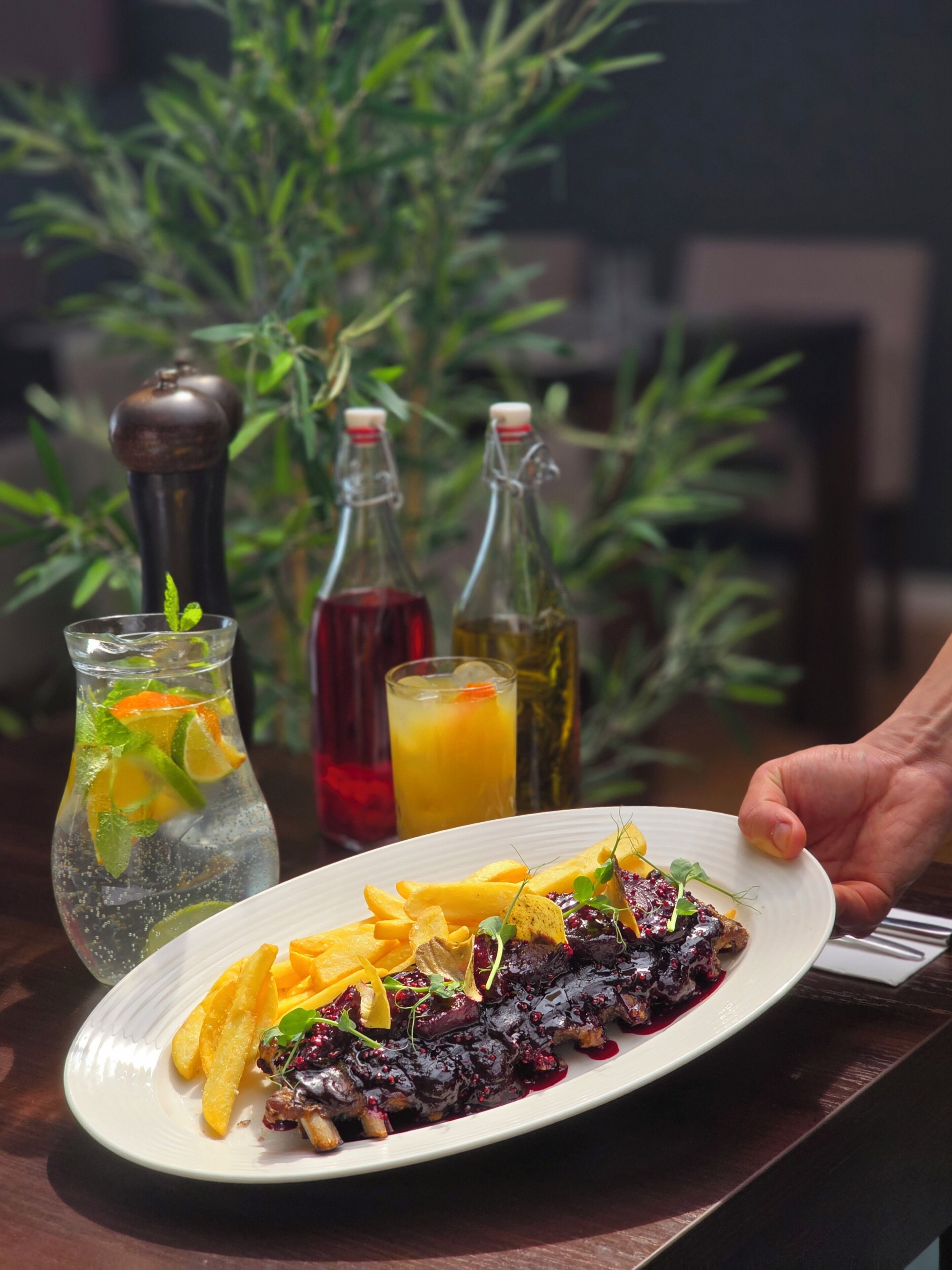 A plate of food with a drink and two bottles on a table.
