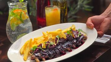A plate of food with a drink and two bottles on a table.