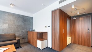 A modern room with a stone wall, a wooden cabinet, a sofa, and a desk. - Terminal Hotel (Wrocław)