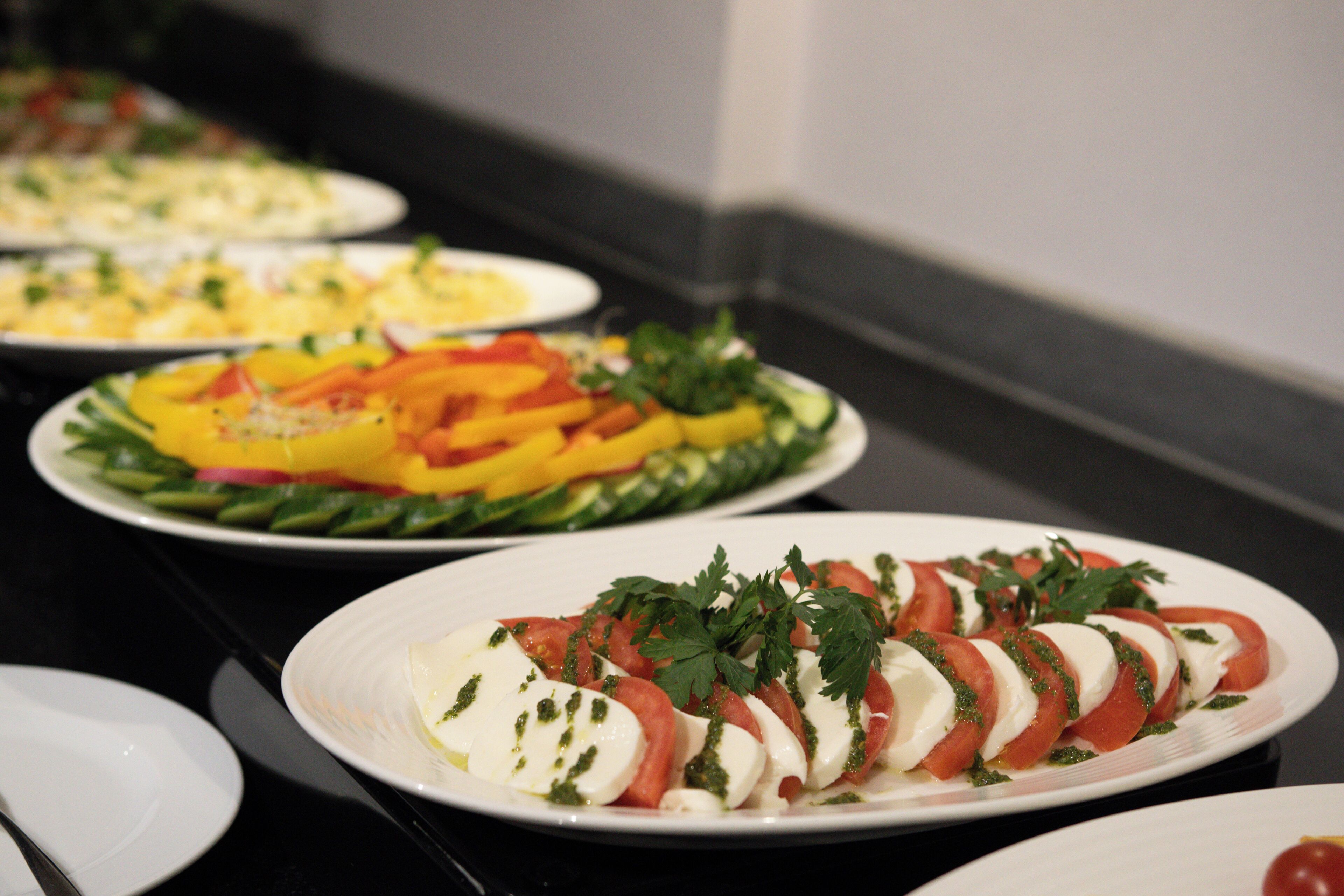 A buffet with various dishes including a plate with sliced tomatoes and mozzarella.