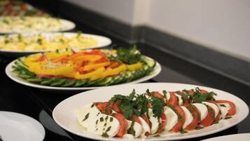 A buffet with various dishes including a plate with sliced tomatoes and mozzarella.