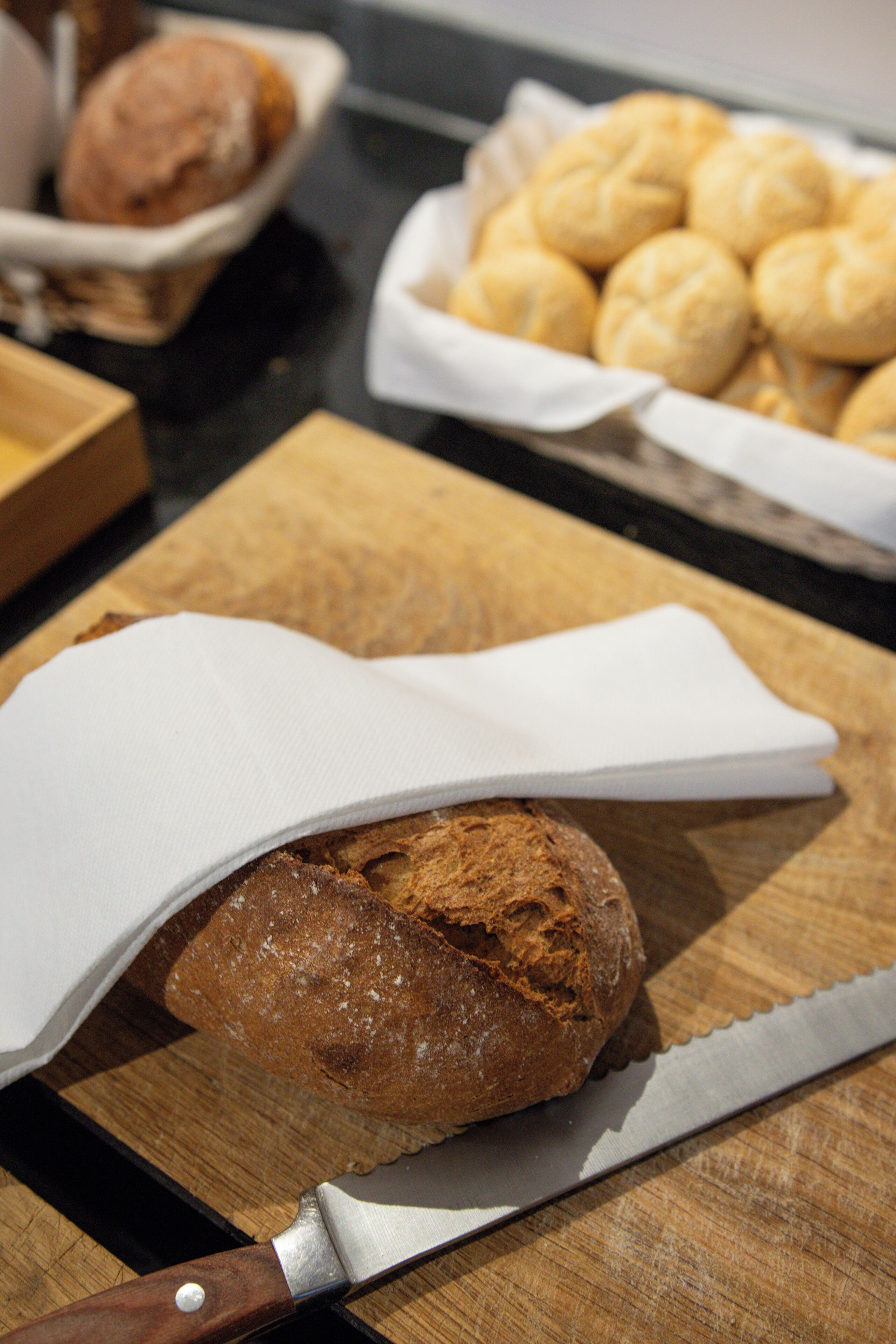 A loaf of bread on a wooden cutting board with a knife beside it.