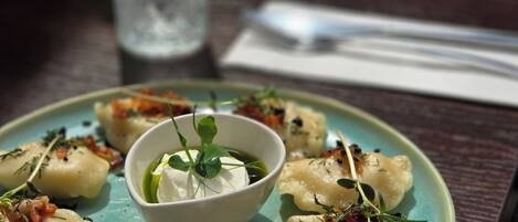 A plate of dumplings with a garnish, a glass of water, and a menu on a table.