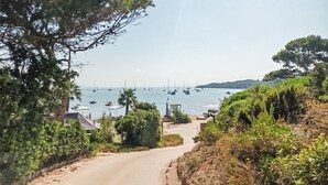 En kystvej der fører til en strand med sejlbåde i vandet.