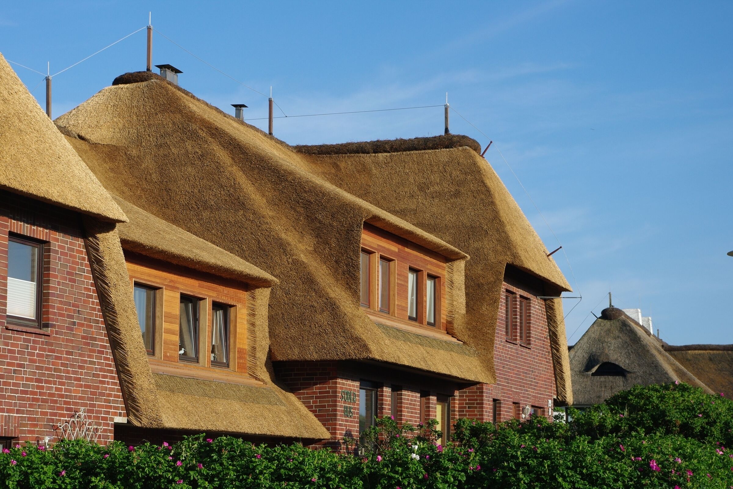 Ein Gebäude mit Strohdächern und Backsteinmauern, mit mehreren Fenstern und einem sichtbaren Schornstein.