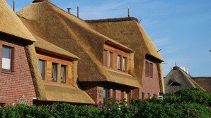 Ein Gebäude mit Strohdächern und Backsteinmauern, mit mehreren Fenstern und einem sichtbaren Schornstein.