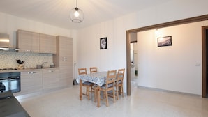 Una cucina moderna con mobili in legno, un tavolo da pranzo con sedie e un lampadario.
