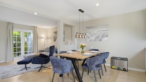 A modern dining area with a wooden table, grey upholstered chairs, and a hanging light fixture. - Beautiful house Uter with terrace and modern furnishings in Westerland (Westerland)