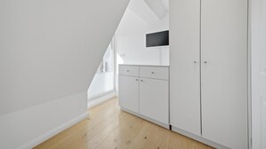 A modern, white interior with a sloped ceiling, wooden flooring, and a built-in TV. - Beautiful house Uter with terrace and modern furnishings in Westerland (Westerland)