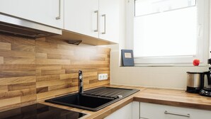 Cozinha moderna com painel de madeira, pia preta e janela com vista para o exterior.