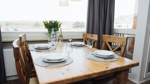 Mesa de jantar posta com pratos, copos e um vaso de flores.