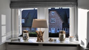 Ein Fenster mit Blick auf ein Backsteingebäude, eine Lampe und dekorative Gläser auf einem Sims.