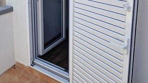 A sliding glass door with a white frame and a white shutter, leading to a dark interior. - Cozy vacation apartment in Smokvica, island of Pag, Dalmatia, Croatia - close to the beach (Smokvica Pag)