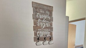 A wooden dining table with a white wire basket and a wall-mounted coffee mug holder with a sign. - Cozy vacation apartment in Smokvica, island of Pag, Dalmatia, Croatia - close to the beach (Smokvica Pag)