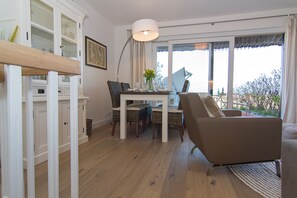 Ein Essbereich mit einem Tisch, gedeckt für vier Personen, umgeben von Stühlen. Es gibt ein großes Fenster mit Blick ins Freie.