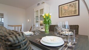 A dining table set with plates, glasses, and cutlery, a vase with flowers, and a framed map on the wall. - Beautiful 3-room apartment with direct view of the mudflats in Rantum (Rantum)