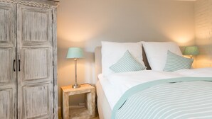 Quarto com cama, mesa de cabeceira, luminária e guarda-roupa.