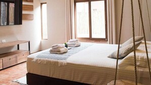 A bedroom with a wooden ceiling, a bed with a hanging swing, a window with curtains, and a bedside table. - w Calm 4BR Villa w Fireplace in Sacred Valley (Calca)