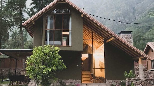 A modern two-story house with a stone foundation, large windows, and a sloped roof. - w Calm 4BR Villa w Fireplace in Sacred Valley (Calca)