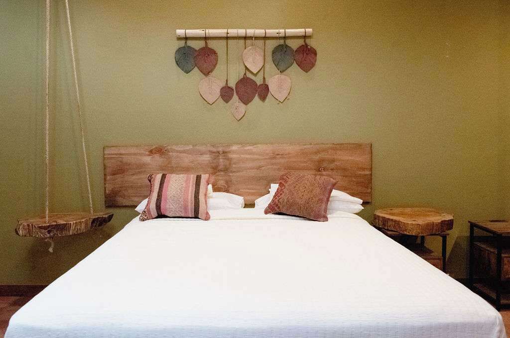 Un lit avec une tête de lit en bois, deux oreillers et une décoration en forme de cœur fixée au mur.