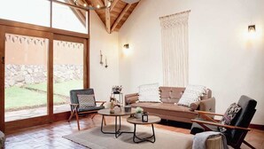 Ein großzügiger Wohnbereich mit einem braunen Sofa, zwei Sesseln, einem Couchtisch und einer großen Schiebeglasdoor zum Außenbereich.
