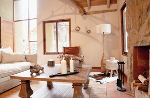 Una sala de estar acogedora con una mesa de madera, un sofá y una chimenea.