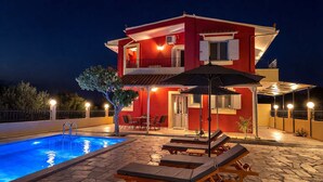 Ein zweistöckiges Haus mit Swimmingpool, Außenmöbeln und einer überdachten Terrasse.