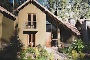 A two-story house with a balcony, a stone chimney, and a garden with various plants and flowers. - w Warm 3BR Villa in Sacred Valley (Calca)