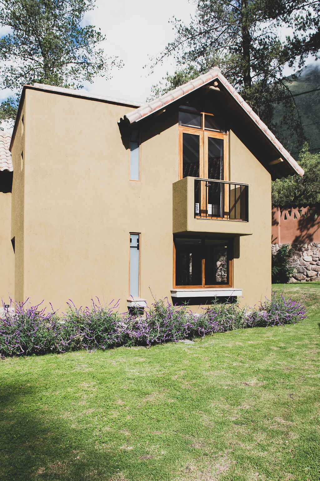 Uma casa moderna de dois andares com varanda, um pequeno alpendre e um gramado bem cuidado.