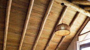 Ein Schlafzimmer mit Holzboden, einem Bett mit weißer Bettwäsche, einem Nachttisch und einem Fenster mit Vorhängen.