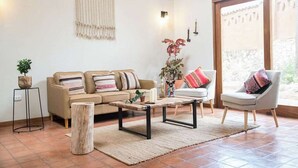 Ein Wohnzimmer mit einer Couch, einem Sessel, einem Couchtisch und einer Pflanze.