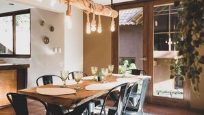 A dining area with a wooden table set for four, surrounded by black chairs. A rustic rope light hangs above the table. - w Peaceful 2BR Riverside Villa in Sacred Valley (Calca)
