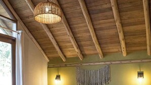 A bedroom with a wooden ceiling, a bed with white bedding, two wall-mounted lamps, and a small bedside table. - w Peaceful 2BR Riverside Villa in Sacred Valley (Calca)
