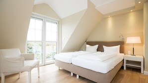 Une chambre avec un grand lit, une chaise, une table de chevet et une fenêtre donnant sur un beau paysage.