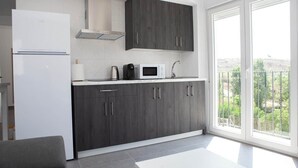 Una cocina moderna con armarios de madera oscura, un refrigerador blanco, un microondas y una cafetera.