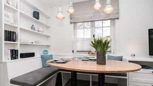 A modern kitchen with white cabinetry, a round wooden table, and a built-in bench. - Haus Friesenperle: Comfortable vacation home with terrace and garden in Westerland (Westerland)