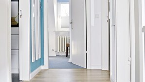 Un passadís amb parets blanques, una paret destacada de blau i un sòl de fusta.