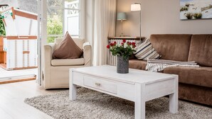 En stue med et hvidt sofabord, en beige sofa og en brun sofa. Der er en vase med røde blomster på sofabordet.