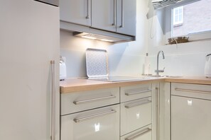 Een moderne keuken met witte kastjes, een roestvrijstalen koelkast en een houten aanrecht.
