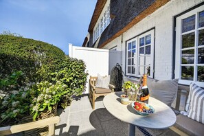 Une terrasse avec une table dressée pour un repas, une bouteille de champagne et un panier en osier.