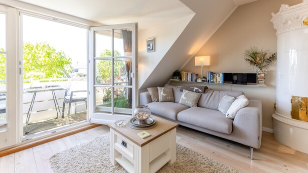 A modern living room with a grey sofa, a coffee table, and a bookshelf. - Beautiful vacation apartment with sauna, indoor pool and fitness room in Keitum (Keitum)