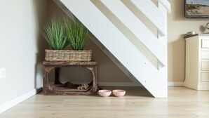 A staircase with a white railing, a wooden bench with a basket and plants, and a pair of pink bowls on the floor. - Beautiful vacation apartment with sauna, indoor pool and fitness room in Keitum (Keitum)