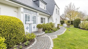 A white house with a grey roof, a paved driveway, and well-maintained hedges. - Beautiful vacation apartment with sauna, indoor pool and fitness room in Keitum (Keitum)