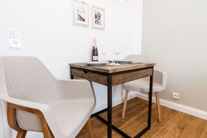A dining area with a wooden table, two white chairs, a bottle of wine, and two glasses. - Modern vacation apartment with sauna, solarium and heated indoor pool in Westerland (Westerland)