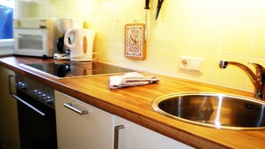 Eine Küche mit Spüle aus Edelstahl, einer Holz Arbeitsplatte, weißen Schränken und einer Mikrowelle.