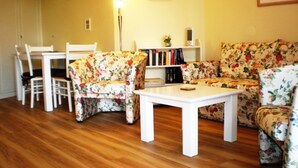 Ein Wohnzimmer mit floralen Möbeln, einem weißen Tisch und einem Bücherregal.