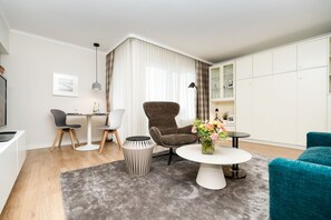 A modern living room with a round coffee table, two armchairs, a small side table, a TV, and a cabinet with glass doors. - Modern vacation apartment with sauna and heated indoor pool in Westerland (Westerland)