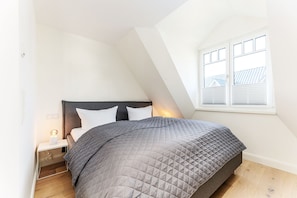 Ein Schlafzimmer mit Bett, Nachttisch und Fenster.