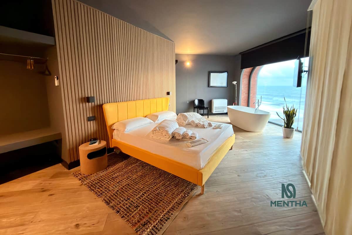 Een moderne slaapkamer met een groot bed, een badkuip en uitzicht op de oceaan.